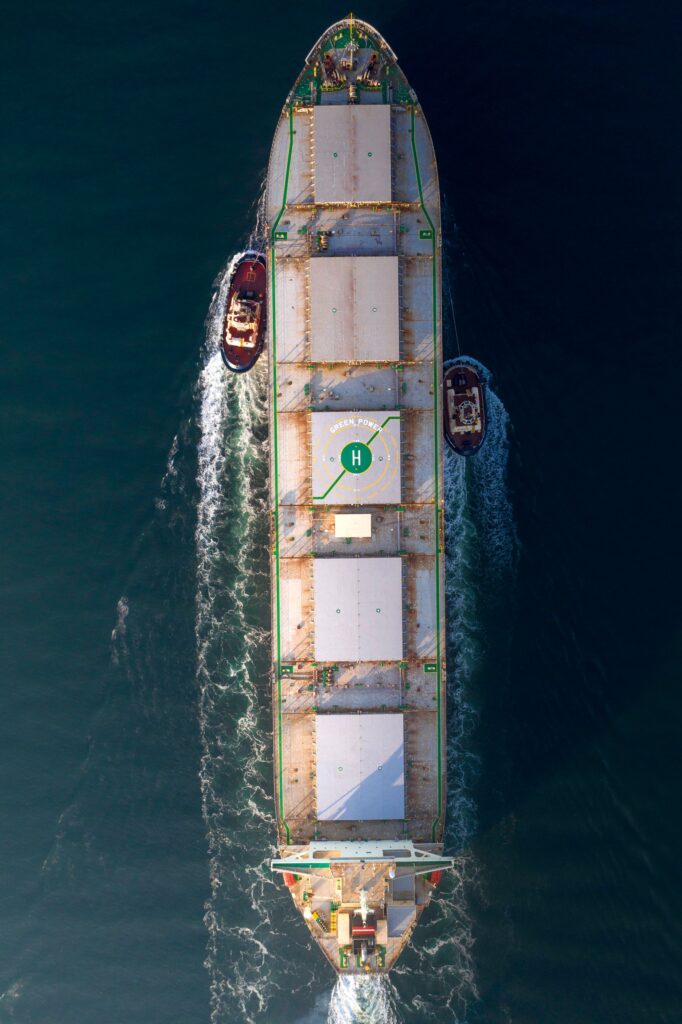 Aerial view of a container ship guided by tug boats at sea